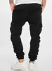 A person wearing black cargo jogging pants and white sneakers, shown from the back. Anteprima dell’immagine prodotto