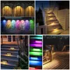 A collage of images showing solar-powered outdoor lights installed on fences, stone walls, and stairs, demonstrating different lighting effects and colors. Produktbild-Vorschau