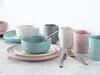 A collection of ceramic tableware, including bowls, plates, and cups, arranged on a light-colored surface. Náhľad obrázku produktu