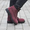 A person wearing burgundy Timberland boots, standing on a paved walkway. Voir les images du produit