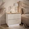 A modern white nightstand with gold accents and LED lighting, placed next to a bed in a bedroom setting. Produktbild-Vorschau
