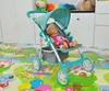 A doll is sitting in a stroller on a colorful play mat. Produktbild-Vorschau