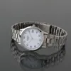A watch is shown on a reflective gray surface. Podgląd zdjęcia produktu