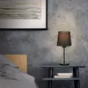 A bedside table with a lamp and books next to a bed. Produktbild-Vorschau