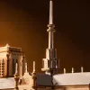 A close-up view of a detailed wooden model of the Notre Dame Cathedral, focusing on the spire and roof. Náhled obrázku produktu