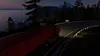 A red semi-trailer truck driving on a winding road at dusk, with a lighthouse visible in the distance. Náhled obrázku produktu