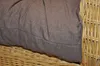A close-up view of a brown cushion placed on a wicker chair. Produktbild-Vorschau