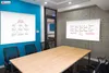 A modern conference room with two whiteboards on display, one showing a flowchart and the other showing graphs. A large wooden table and chairs are in the foreground. Produktbild-Vorschau