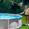 A woman is cleaning an above-ground swimming pool with a skimmer net. Anteprima dell’immagine prodotto