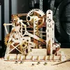 A wooden marble run model with several silver marbles on a surface covered in wood shavings. Voir les images du produit