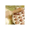 A close-up view of a ravioli maker with dough and filling, and a wooden rolling pin. Náhled obrázku produktu