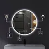 A round LED mirror with various feature icons around it, mounted above a sink in a modern bathroom. Náhled obrázku produktu