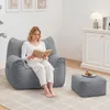 A woman sits on a large gray beanbag chair reading a book, with a matching ottoman in front of her. Náhľad obrázku produktu