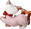 A ceramic figurine of a cat-like creature wearing a pink outfit and a red bow, with a gift box behind it. Produktbild-Vorschau