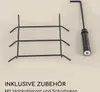 A close-up of a grill grate and a poker tool, with text indicating included accessories. Produktbild-Vorschau