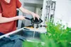 A person is rinsing a pot in a kitchen sink. Voir les images du produit