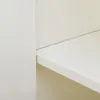 A close-up view of a white shelf and the side of a cabinet. Anteprima dell’immagine prodotto