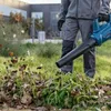 A person is using a blue leaf blower to clear leaves and grass from a lawn. Produktbild-Vorschau