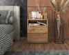A bedroom scene featuring a bedside table next to a bed, with decorative items on the table and a vase with dried flowers in the background. Náhled obrázku produktu