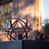Two decorative metal spheres with candles in front of a wooden structure. Voir les images du produit