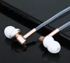 A pair of gold and white in-ear headphones rests on a dark, reflective surface, possibly a smartphone. Produktbild-Vorschau