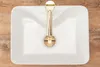 A white rectangular sink with a gold faucet, placed on a wooden surface. Anteprima dell’immagine prodotto