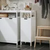 A laundry room setting with white storage cabinets and a wooden step stool. Produktbild-Vorschau