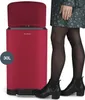 A person is standing next to a red trash can, demonstrating its use. Voir les images du produit