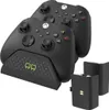 A black dual charging dock with two Xbox controllers and two rechargeable battery packs. Produktbild-Vorschau