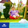 A young girl is happily swinging on a red swing in a backyard setting. Produktbild-Vorschau