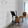 Acoustic panels are shown on a wall behind a guitar, music stand, and chair. Náhled obrázku produktu