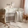 A baby crib with bedding and a basket next to it, in a nursery setting. Anteprima dell’immagine prodotto