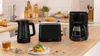 A kitchen counter with a coffee maker, toaster, and kettle, along with some food and drink. Podgląd zdjęcia produktu