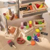 A collection of wooden toy food items and a play shop counter, arranged on a wooden floor. Náhľad obrázku produktu