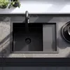 A top-down view of a black kitchen sink with a faucet and a draining board. Anteprima dell’immagine prodotto