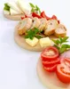 A food platter with cheese, bread, tomatoes, and herbs on wooden boards. Podgląd zdjęcia produktu