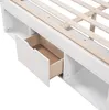 A close-up view of the side of a white bed frame, showing an open drawer and storage compartments. Podgląd zdjęcia produktu