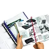 A person is holding open a catalog or brochure, showing various office supplies and electronics. A binder is visible on the left. Produktbild-Vorschau