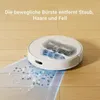 A white robot vacuum cleaner is shown on a wooden floor, demonstrating its cleaning function with blue visual effects indicating suction and debris collection. Voir les images du produit