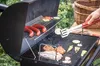 A person is grilling sausages and meat on a BBQ grill outdoors. Podgląd zdjęcia produktu