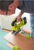 A person is using a yellow and black jigsaw to cut a wooden plank. Produktbild-Vorschau