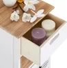 A close-up view of a drawer in a white dresser, revealing two candles inside. The top of the dresser is made of wood and decorated with white flowers. Produktbild-Vorschau