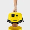 A hand holding a yellow Kärcher vacuum cleaner head over a filter. Produktbild-Vorschau
