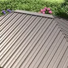 A close-up view of a brown metal roof of a garden pavilion, with green foliage and pink and purple flowers in the background. Produktbild-Vorschau
