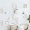 Four white cube shelves are mounted on a white wall, arranged in an offset pattern. Some shelves contain books and decorative items. Náhled obrázku produktu