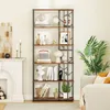 A tall, multi-shelf bookcase filled with decorative items and books, placed next to a fireplace and a sofa in a living room. Produktbild-Vorschau