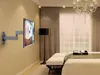 A modern bedroom with a wall-mounted TV and a floor lamp. Produktbild-Vorschau