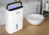 A white N'oveen DH350 dehumidifier is placed on a wooden countertop next to a white sink in a bathroom. Náhľad obrázku produktu