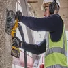 A construction worker is using a DeWALT Akku-Mauernutfräse to cut into a concrete wall. Voir les images du produit