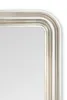 A close-up view of the corner of a mirror with a decorative silver frame. Voir les images du produit